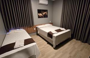 a hotel room with two beds and curtains at FLATS MELO unimontes in Montes Claros