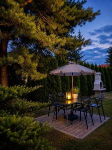 a table and chairs with an umbrella on a patio at Szept Fal & Minigolf in Rewal