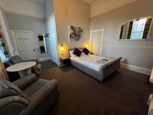 a bedroom with a bed and a couch and a table at The Jubilee Hotel East - with NEWLY REFURBISHED SPA FACILITIES - GAMESPIT - AND SMOKEHOUSE in Weymouth