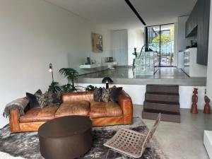a living room with a brown leather couch and a kitchen at Phegans Bay Waterfront Haven in Blackwall