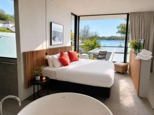 a hotel room with a large bed and a balcony at Phegans Bay Waterfront Haven in Blackwall