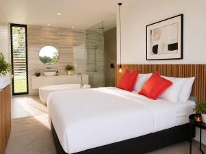 a bedroom with a large white bed and a bath tub at Phegans Bay Waterfront Haven in Blackwall