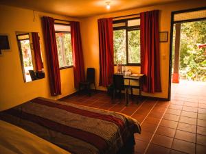 a bedroom with a bed and a table and windows at Hotel Guaitipan Ancestral in San Agustín