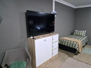 a small bedroom with a flat screen tv and a bed at 42AtSouth in Vryheid