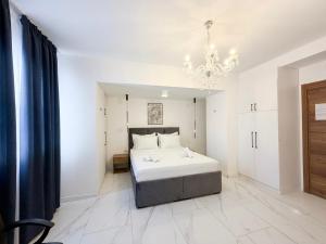 a white bedroom with a bed and a chandelier at Maison Mark Luxury Suites & Spa in Belgrade +5 photos