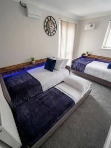 a bedroom with two beds and a clock on the wall at Sea-View Luxury Apartment sleeps 5 - Pet Friendly - Fast WiFi - Off Street Parking - Contractors Dream!!! in Sheerness