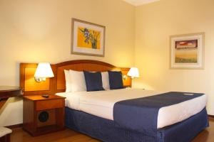 a hotel room with a large bed and a desk at Summit Suites Jundiai in Jundiaí