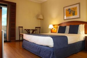 a hotel room with a large bed and a table at Summit Suites Jundiai in Jundiaí +6 photos
