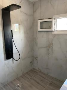 a bathroom with a shower with a television on the wall at Georgia's House Olympiada in Olympiada +14 photos