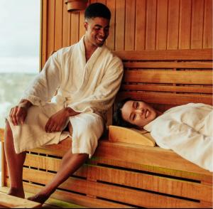 a man and a woman sitting on a bed at Fehntjer Ferienhof nahe Idasee in Ostrhauderfehn