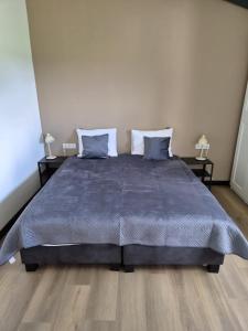 a bedroom with a large bed with two tables at Bed&Boerderij De Veldmuis in Eemdijk