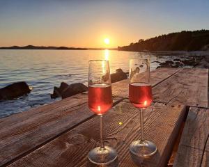 two glasses of wine sitting on a table near the water at Relax Camp Pitches in Pakoštane