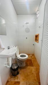 a white bathroom with a toilet and a sink at Mini Suítes - Centro de Tutóia in Tutóia