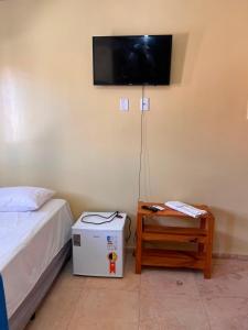 a bedroom with a bed and a television on the wall at Mini Suítes - Centro de Tutóia in Tutóia