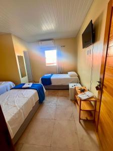 a hotel room with two beds and a television at Mini Suítes - Centro de Tutóia in Tutóia