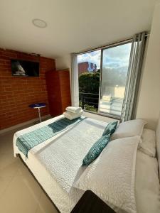 a large bed in a room with a large window at Living Montes in Medellín