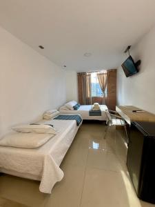 a room with two beds and a television in it at Living Montes in Medellín