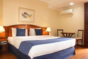 a bedroom with a large bed with blue and white sheets at Summit Suites Jundiai in Jundiaí