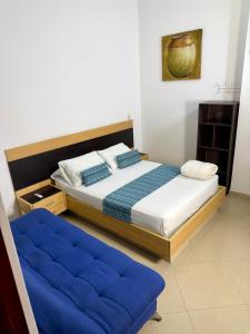 a bedroom with a bed and a blue ottoman at Living Montes in Medellín +37 photos