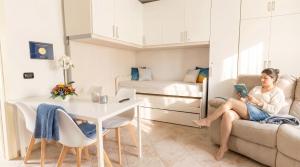 a woman sitting on a couch reading a book in a living room at The Sea Wind Apartments & Suites in Palau +45 photos