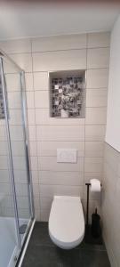 a white bathroom with a toilet and a shower at Ferienhaus Wellenklang in Glowe
