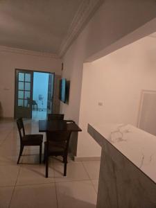 a living room with a table and chairs and a kitchen at Le gite 2 in Libreville