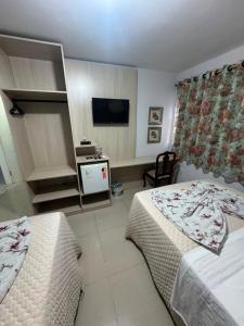 a hotel room with two beds and a television at Hotel Guerra - Pousada Montebelo in Jaguaruna