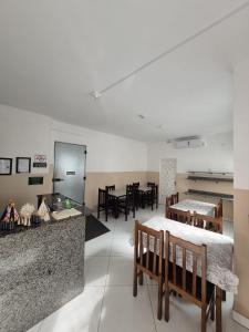 a large room with tables and chairs and a kitchen at Pousada Bela Rainha in Aparecida