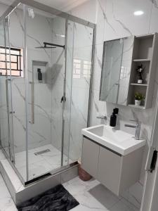 a white bathroom with a shower and a sink at Gabstel Apartments in Kitwe