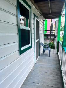 a porch of a house with a chair on it at Garden Lodge Hotel in Placencia