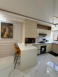 a kitchen with a white counter and chairs in it at Gabstel Apartments in Kitwe +2 photos