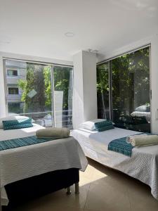 two beds in a room with a large window at Living Montes in Medellín