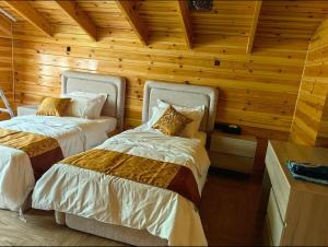 two beds in a room with wooden walls at اكواخ لاكجري ابها 2 in Abha