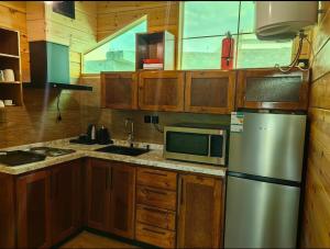 a kitchen with wooden cabinets and a stainless steel refrigerator at اكواخ لاكجري ابها 2 in Abha