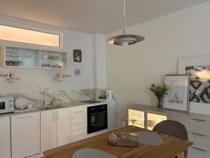 a kitchen with white cabinets and a wooden table at Central Park View Apartment in Dobrich +2 photos