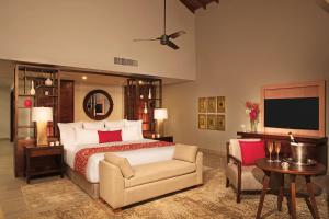 a bedroom with a bed and a chair and a tv at Dreams Dominicus La Romana Resort & Spa in Bayahibe