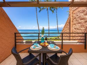 a table with food and wine on a balcony with the ocean at Kuleana 613 1 Bdrm condo in Kahana +36 photos