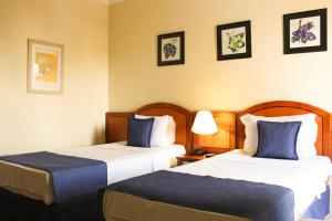 a hotel room with two beds with blue pillows at Summit Suites Jundiai in Jundiaí