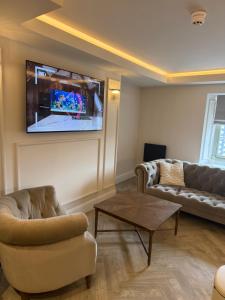 a living room with a couch and a tv on the wall at Oat & Olive Apartments - Alnwick in Alnwick