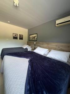 a bedroom with two beds with a blue blanket at Hotel Guerra - Pousada Montebelo in Jaguaruna