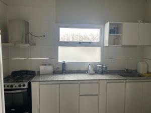 a white kitchen with a stove and a window at Coty A in Saladillo
