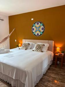 a bedroom with a large white bed with a plate on the wall at Trindade - Suíte Mandala in Trindade