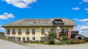 a large yellow building with windows and a flag at Reitpark Gstöttner in Schönau im Mühlkreis