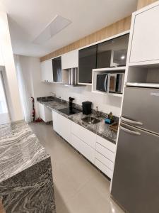 a kitchen with white cabinets and a stainless steel refrigerator at Apt Premium com Vista Panorâmica e Lazer Completo in Joinville