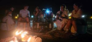 a group of people sitting around a bonfire at night at Luxury Desert Queen Camp in Merzouga