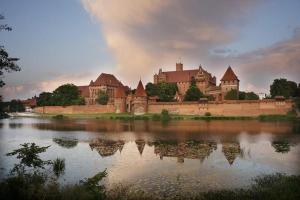 a large castle sitting on top of a body of water at Lawki Booking-Na Strychu in Ławki