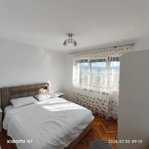 a white bedroom with a bed and a window at Apartament -BeaSarah-Orsova in Orşova