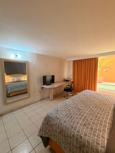 a hotel room with a bed and a desk and a television at Plaza Inn Express in Tapachula