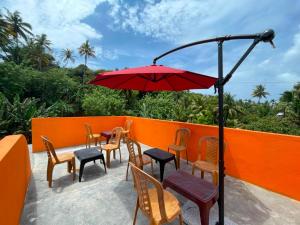 a patio with tables and chairs and a red umbrella at WILD PARADISE Apt in Unawatuna