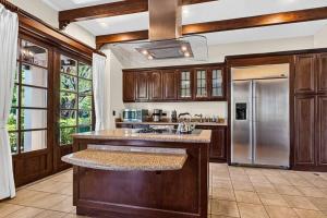 a kitchen with wooden cabinets and a stainless steel refrigerator at Resort Villa Pool Golf & Beach Access in Playa Avellana